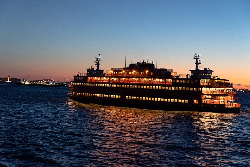 A Staten Island ferry lit up at dusk on New York Harbor