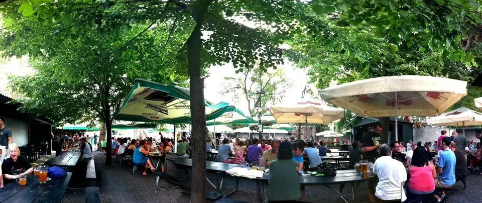 Long tables under the trees and umbrellas of the Bohemian Hall beer garden